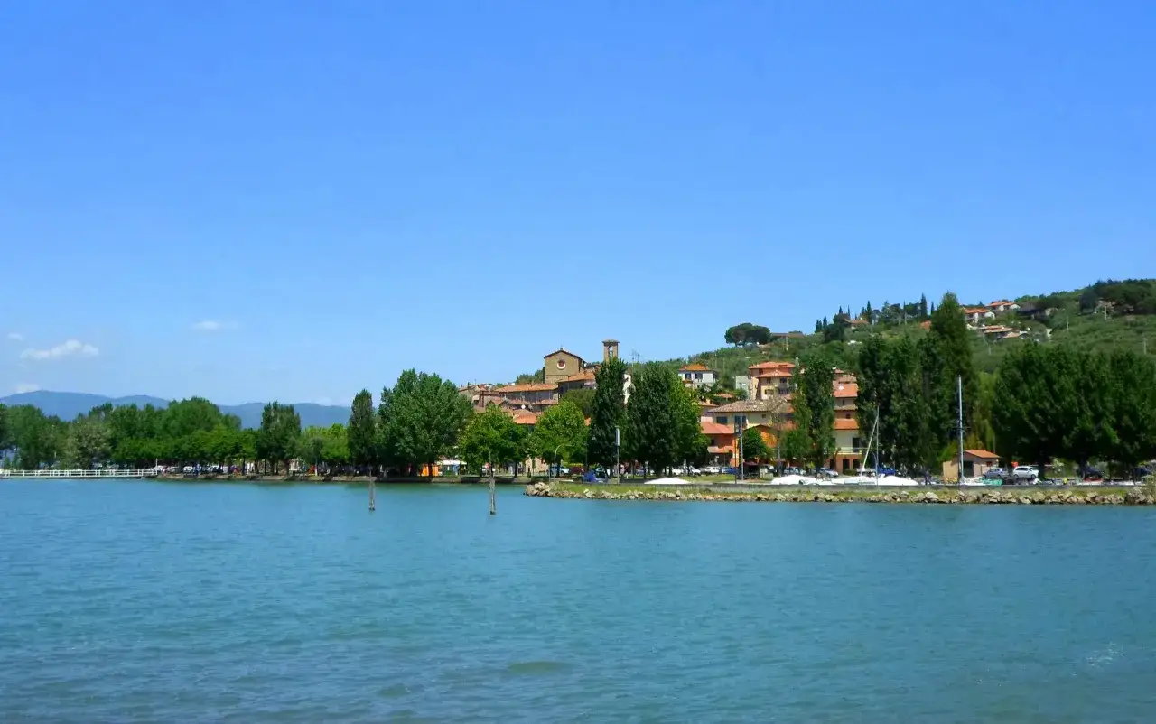 San Feliciano cosa vedere: un borgo sul lago con case colorate, alberi verdi e un cielo azzurro.