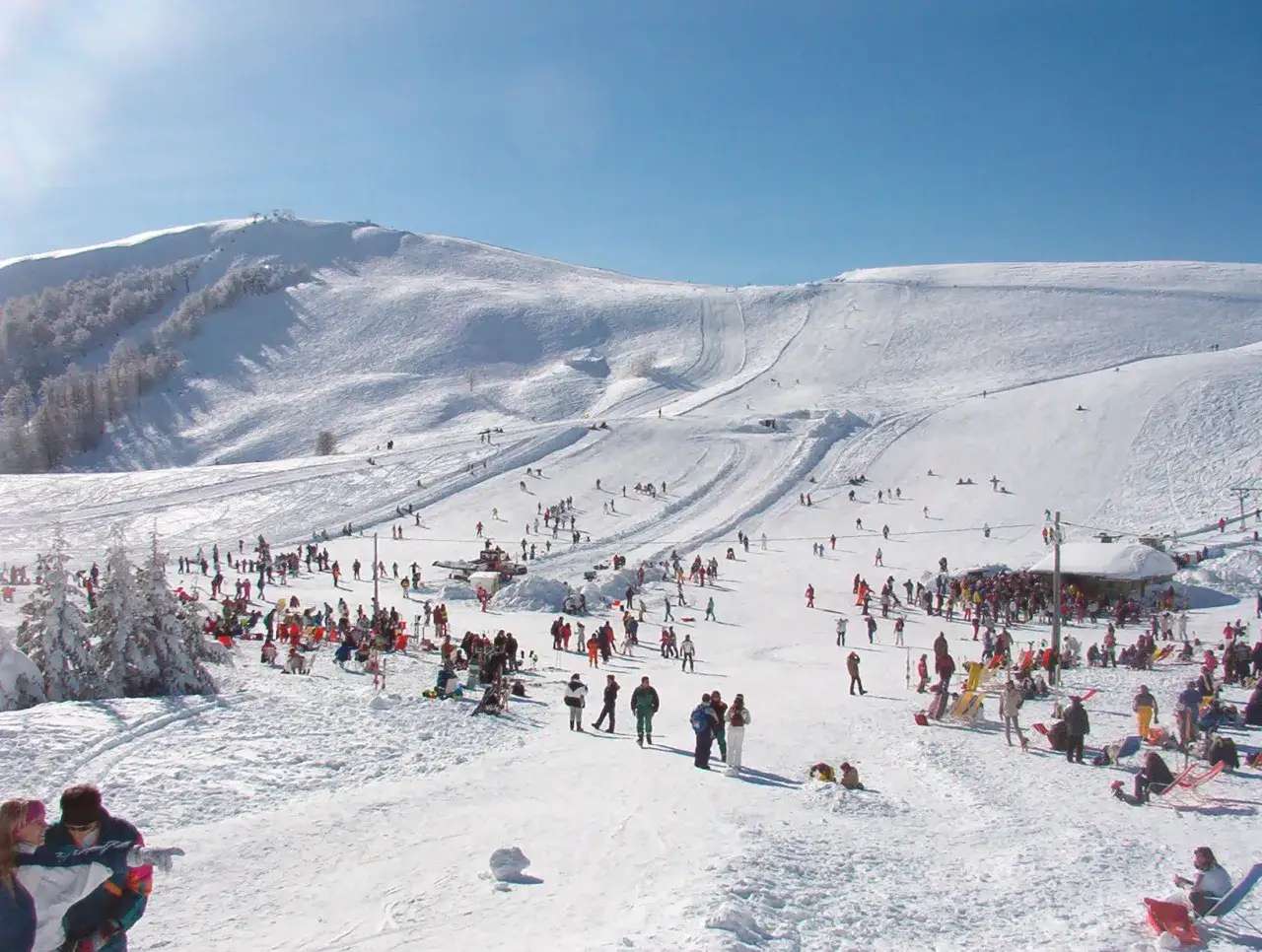 Un'affollata stazione sciistica, ideale per chi cerca dove sciare nel Lazio, con piste innevate, skilift e persone che si divertono sulla neve.