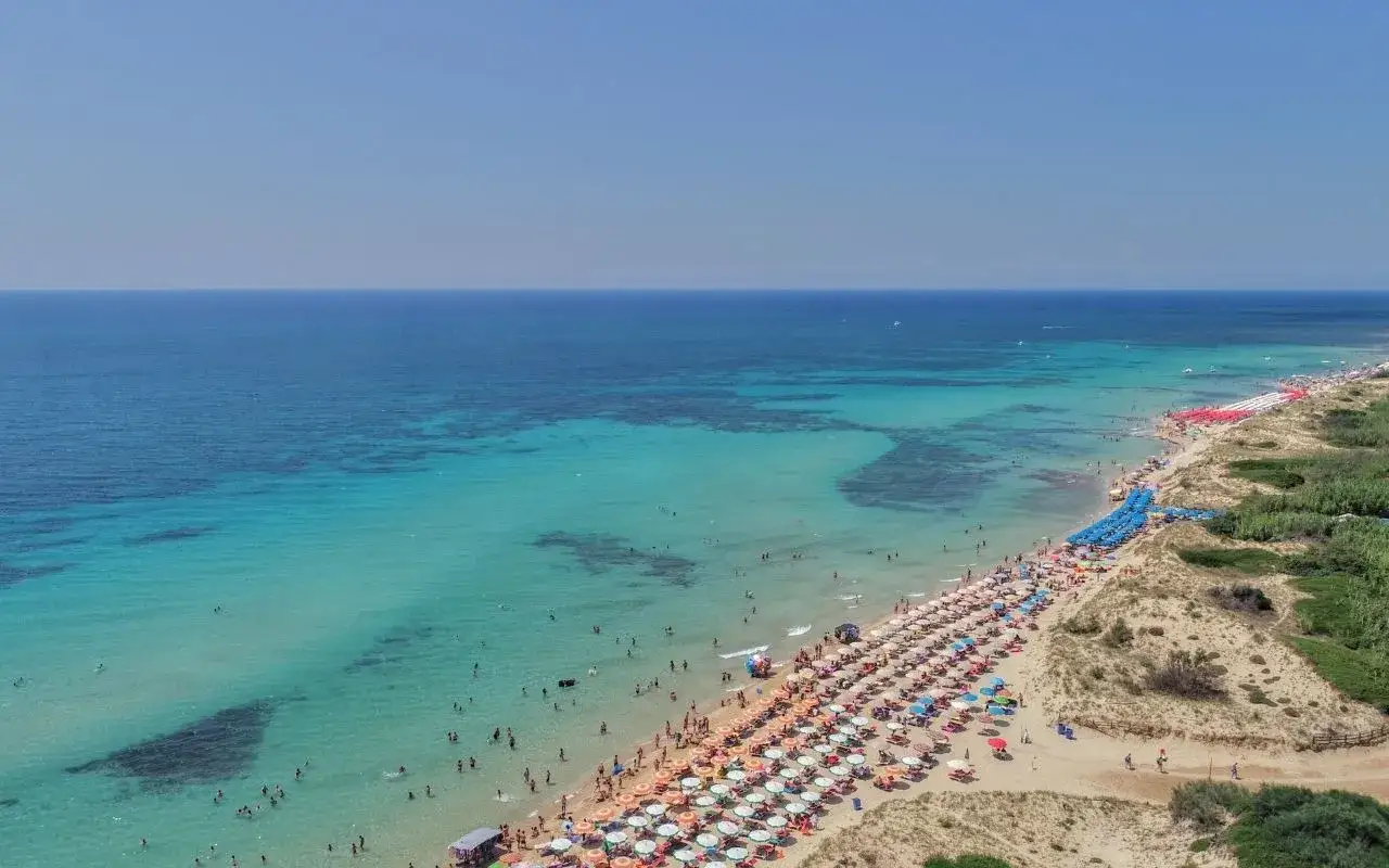 Le Maldive del Salento, dove sono? In questa spiaggia affollata con ombrelloni colorati e acque cristalline.