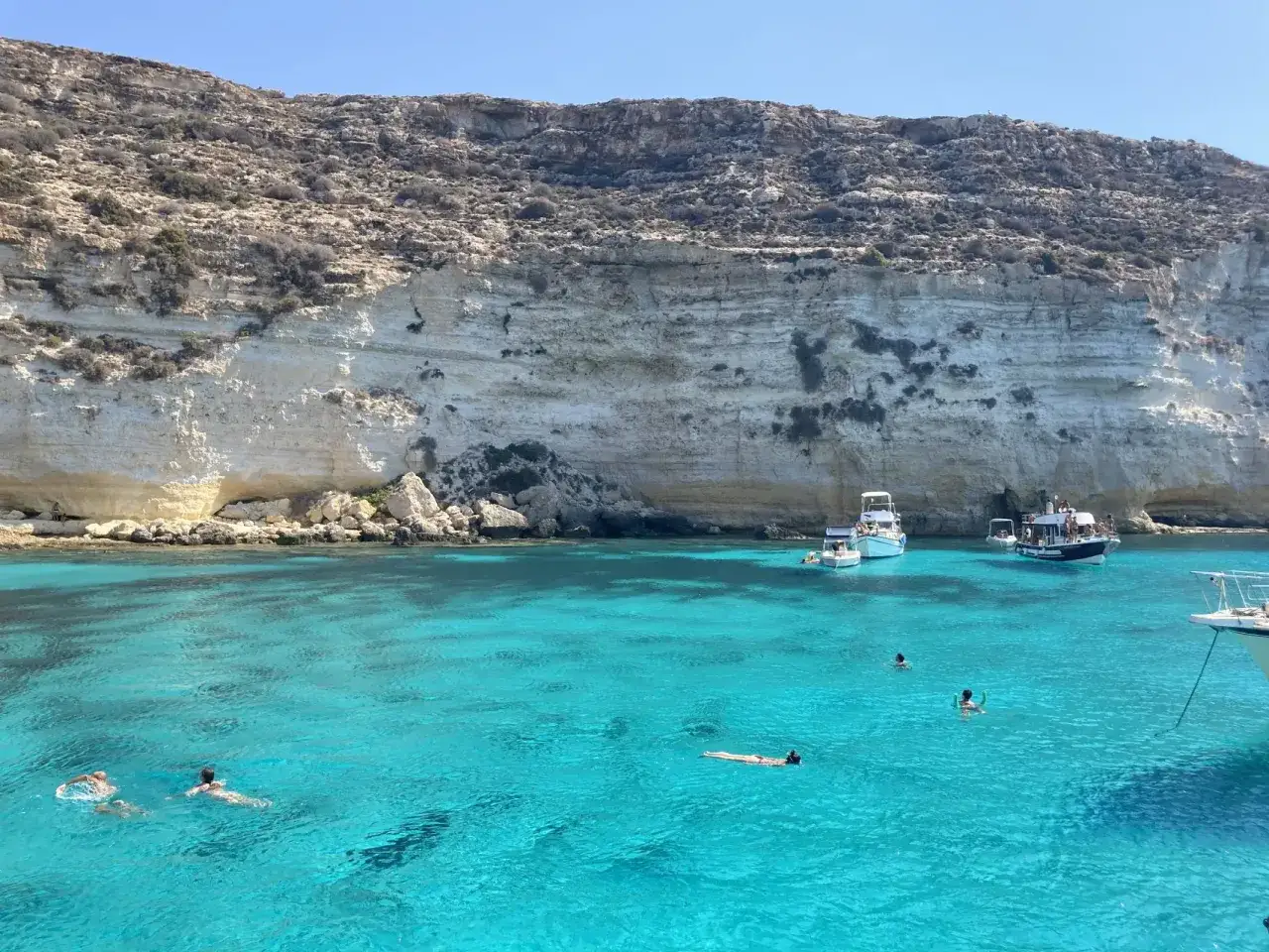 Acque cristalline e scogliere bianche: ecco dove si trova Lampedusa, un paradiso per nuotare e godersi il sole.