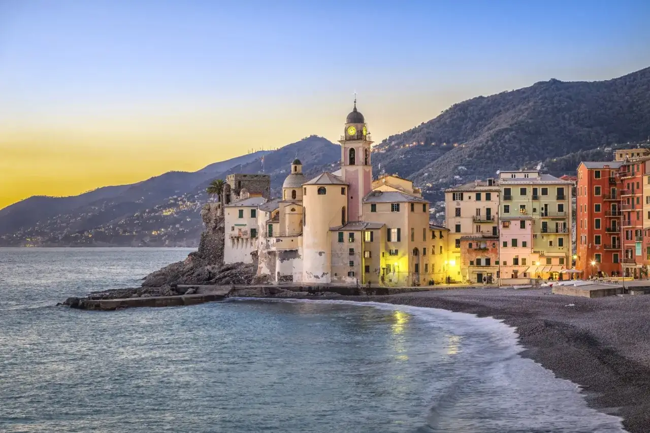 Camogli al tramonto, con le case colorate che si affacciano sulla spiaggia d'inverno e il mare calmo.