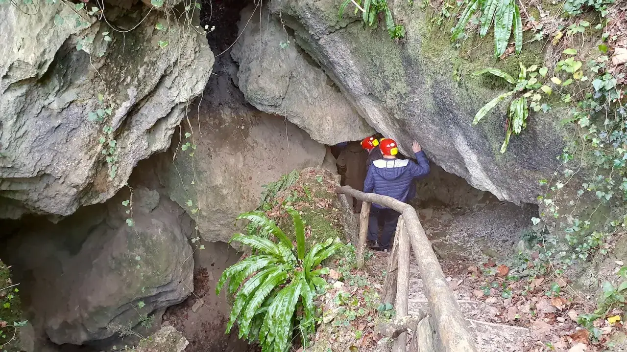 Esploratori in un ingresso roccioso della Valconca, Rimini, con caschi gialli e rossi, pronti a scoprire i segreti della grotta.