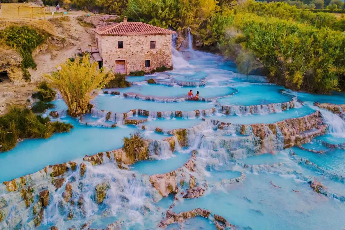 Coppia rilassata nelle vasche naturali delle cascate, un'opera d'arte termale che incanta con le sue acque azzurre e la natura rigogliosa.