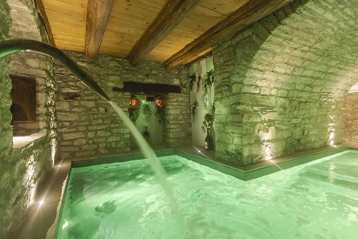 Un'oasi di relax nelle terme Appennino Tosco Emiliano. Acqua verde smeraldo, pareti in pietra e soffitto in legno creano un'atmosfera magica.