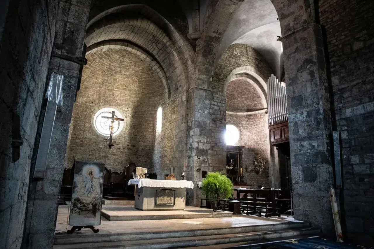 Interno di una chiesa romanica, con altare, crocifisso e organo. Un luogo suggestivo da scoprire: Berceto cosa vedere.