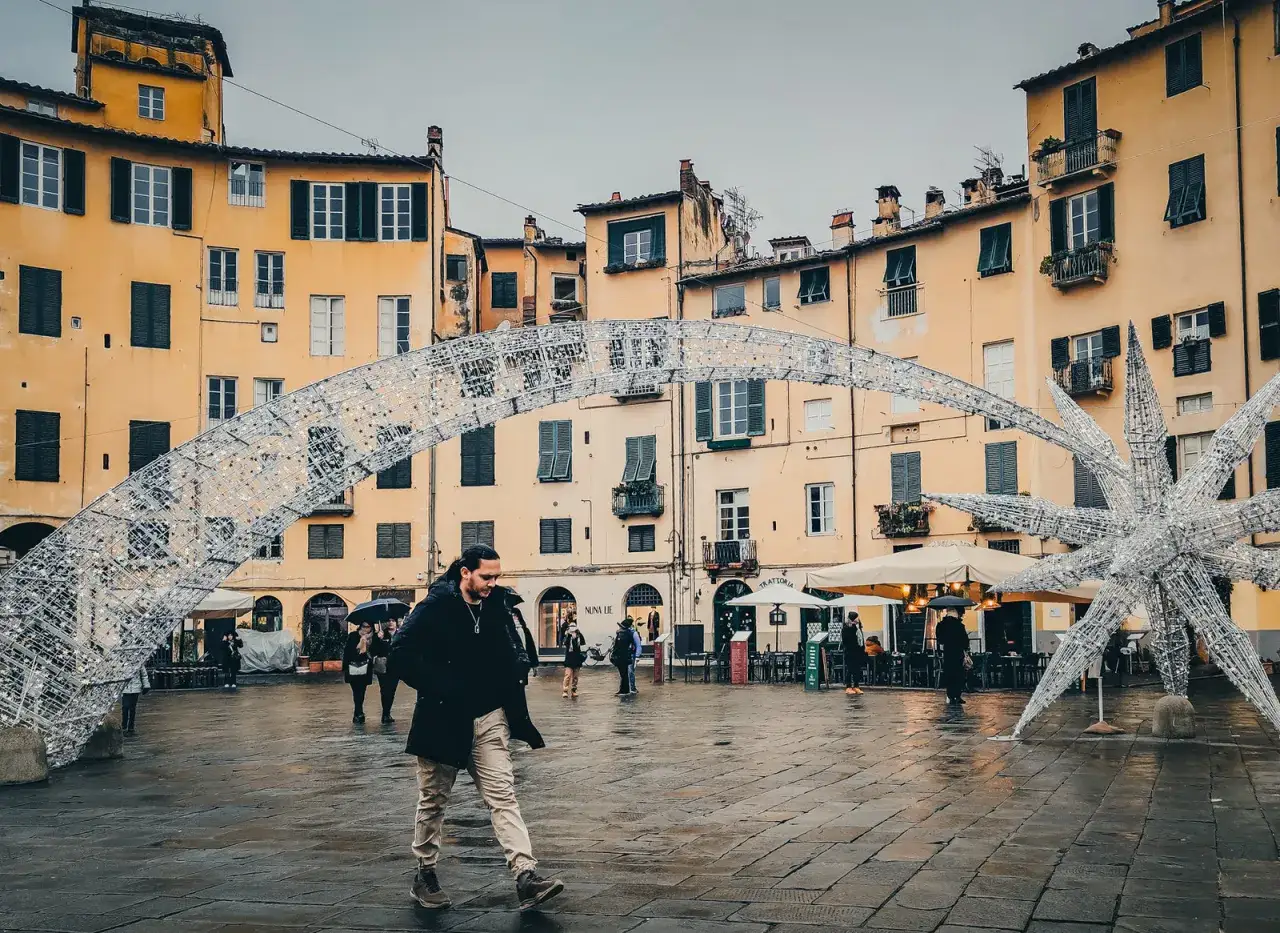 Passeggiata nella piazza di Lucca, con un uomo che cammina sotto un arco luminoso e una stella decorativa.