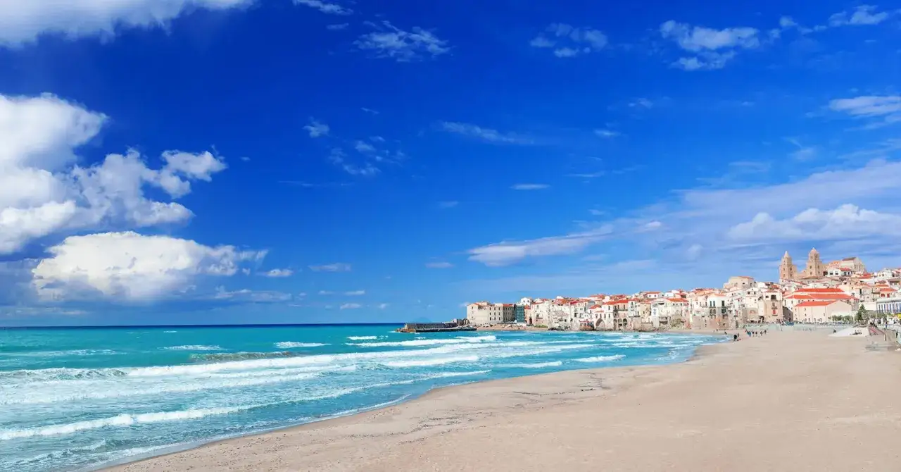 La spiaggia di Cefal&ugrave;, con le sue acque turchesi e la citt&agrave; arroccata sullo sfondo, invita a una giornata di sole e relax.