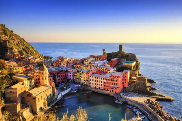 Coloratissimi borghi sul mare aggrappati alla scogliera, con il sole che illumina le case e il blu intenso del mare.