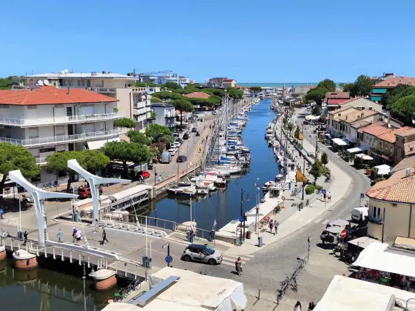 Un canale navigabile a Cervia, dove si trova un vivace porto turistico con barche a vela ormeggiate e case colorate lungo le rive.