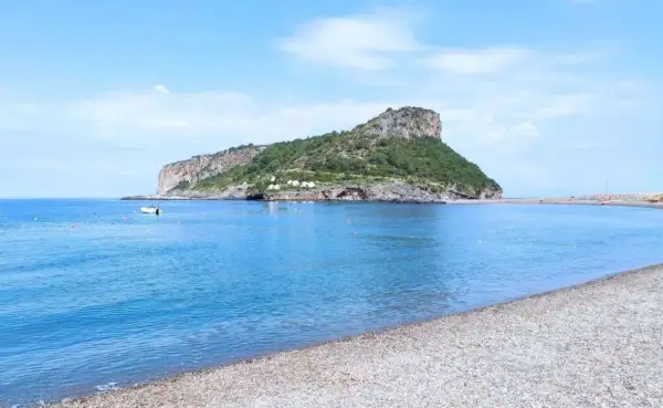 Acque azzurre e una spiaggia di ciottoli nel **golfo di Policastro**, con un'isola verdeggiante sullo sfondo.