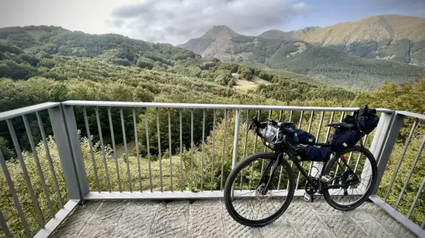 Bicicletta da cicloturismo pronta per esplorare l'Appennino Tosco Emiliano, con un panorama mozzafiato di boschi e montagne.