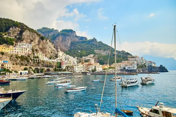 Un incantevole mare a Napoli, con un borgo colorato aggrappato alla scogliera e barche che ondeggiano nell'acqua cristallina.