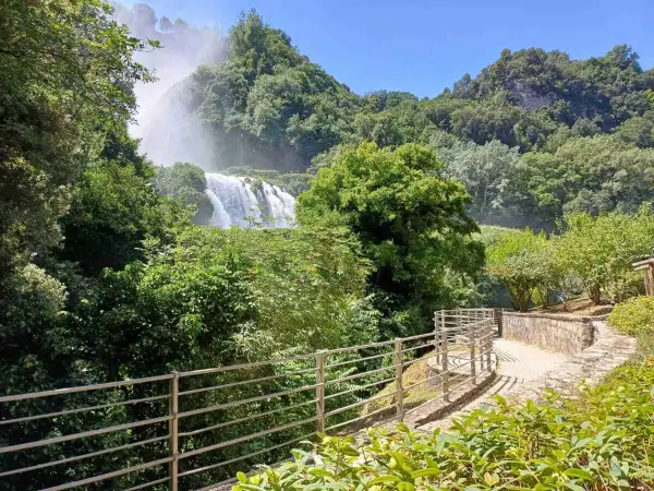Sentiero panoramico nella Valnerina con la cascata che si intravede tra il verde lussureggiante.