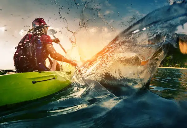 Persona in kayak crea un'onda spettacolare, un'immagine perfetta per le vacanze sportive.