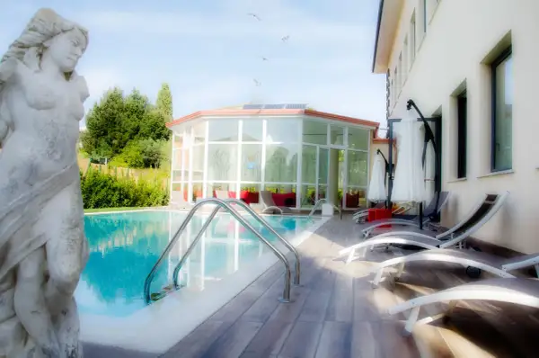 Statua classica vicino alla piscina, con un edificio moderno e un giardino lussureggiante. Un'oasi di relax a Gambassi Terme.