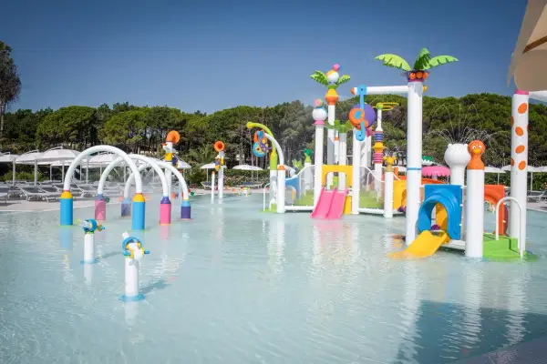 Area giochi acquatica colorata con scivoli e spruzzi d'acqua, perfetta per divertirsi alle terme Lignano.