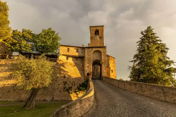 Antica porta di Montegridolfo cosa vedere: un borgo medievale con torre campanaria e vicoli acciottolati, immerso nel verde.
