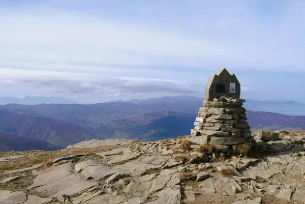 Cairn in pietra sulla cima del monte più alto Emilia Romagna, con vista panoramica sulle colline sottostanti.