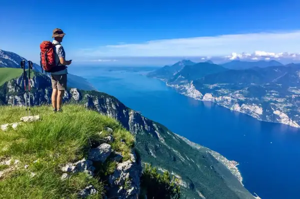 Escursionista ammira il panorama mozzafiato dal Monte Baldo. Cosa vedere: il lago blu intenso e le montagne verdi.