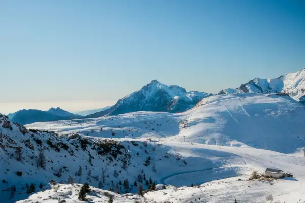Un paesaggio innevato con piste da sci e una baita, una montagna vicino Milano a 1 ora di distanza.