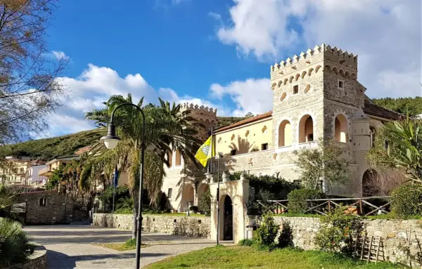 Antico palazzo con torri merlate, palme e un giallo vessillo, incantevole scenario per le terme naturali Cilento.