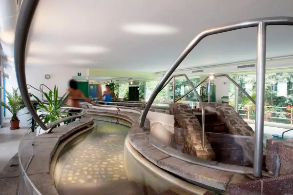 Piscine interne con acqua calda e pietre sul fondo, un percorso rilassante nei bagni di Rabbi.