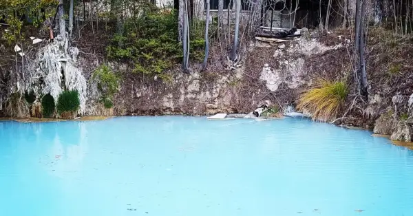 Acque azzurre e torbide delle terme di Cotilia, con vegetazione rigogliosa e rocce erose.