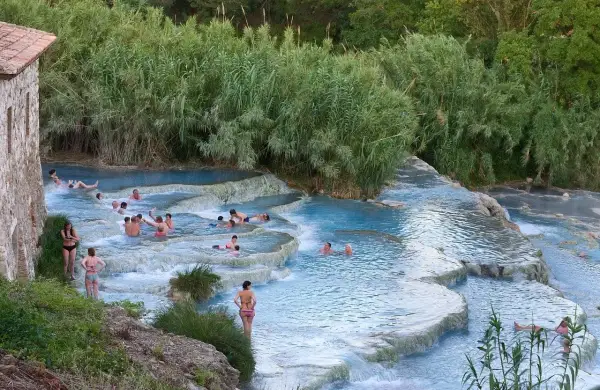 Persone si rilassano nelle cascate termali naturali. Un luogo ideale per scoprire le terme Pavia prezzi.