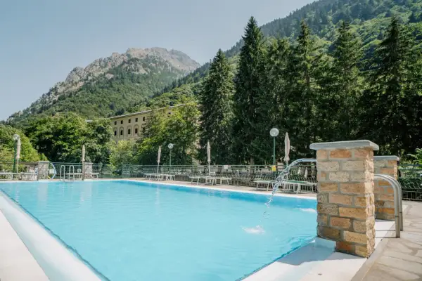 Piscina con acqua azzurra e montagne verdi sullo sfondo, un'oasi di relax alle terme di Valdieri.