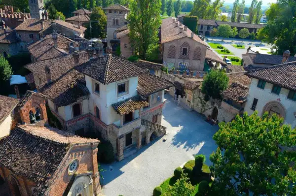 Un borgo fiabesco vicino Piacenza, con tetti in cotto e torri medievali, immerso nel verde.