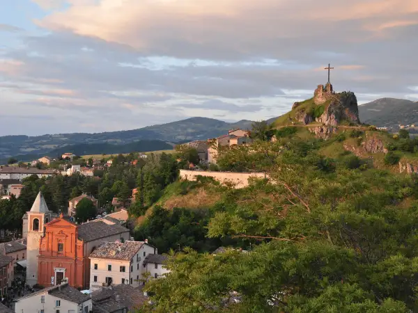 Panoramica di Pennabilli, Rimini, con la chiesa e la rocca con la croce che domina il paesaggio collinare al tramonto.
