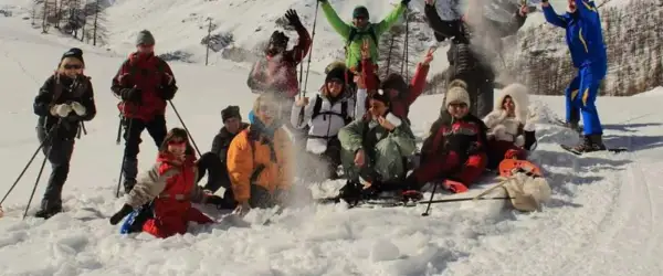 Un gruppo di amici si diverte con le ciaspolate in Val d'Aosta, tra risate e lanci di neve.