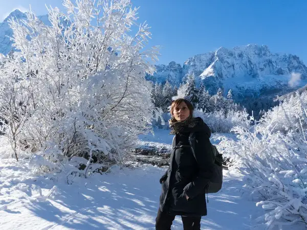 Donna con zaino in un paesaggio invernale innevato, montagne sullo sfondo. Val Saisera incanta con la sua bellezza.