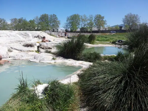 Persone rilassate nelle piscine naturali di acqua termale, un'oasi di pace tra rocce bianche e vegetazione rigogliosa, un vero paradiso per chi cerca le piscine carletti.