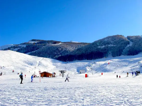 Piste innevate e sciatori in azione, un perfetto esempio di dove si scia in Abruzzo. Montagne innevate e cielo azzurro.