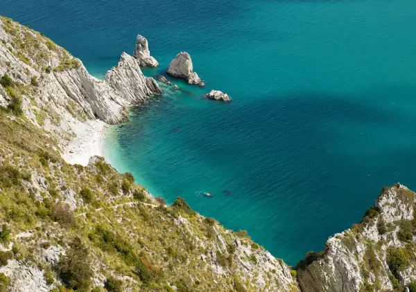 Scogliere bianche e mare turchese in una splendida località sulla riviera del Conero. Una piccola spiaggia nascosta e faraglioni emergono dall'acqua cristallina.