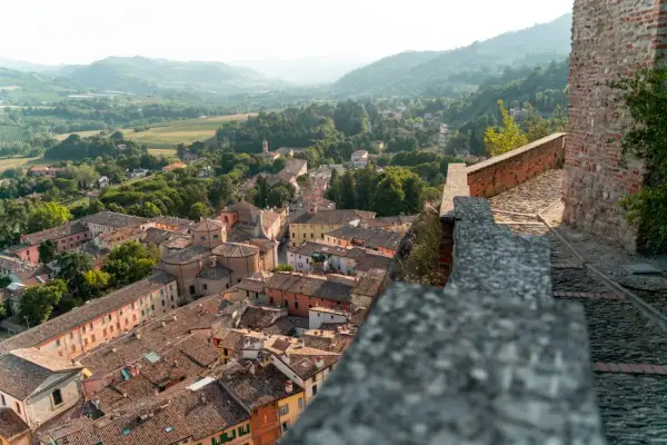 Panoramica di **borghi vicino Reggio Emilia** con tetti in cotto e colline verdi sullo sfondo.