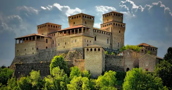 Roccastraordinaria di Torrechiara, un gioiello incastonato tra le colline di Parma, Emilia Romagna, con torri imponenti e un cielo drammatico.